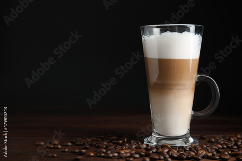 Obraz na płótnie Delicious latte macchiato and coffee beans on wooden table, space for text