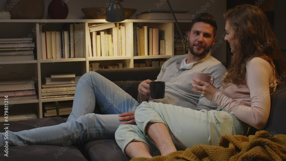 couple relaxing on a sofa drinking coffee and talking couple relaxing on a sofa drinking coffee and talking