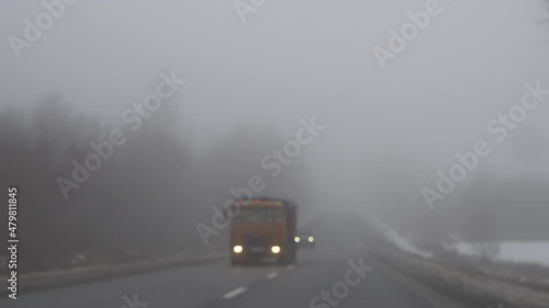 Wallpaper Mural Defocused foggy road with truck and car driving with headlights on, leafless trees along way, snow lying on road sides, tracking shot. Dangerous trip at nasty weather in countryside. Concept of travel Torontodigital.ca