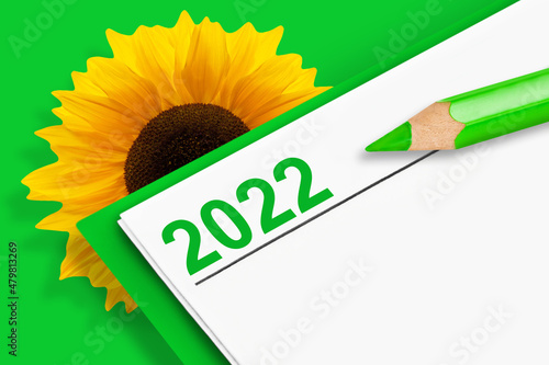 Kalender 2022 Klimaschutz mit Sonnenblume und Stift auf grünem Hintergrund
