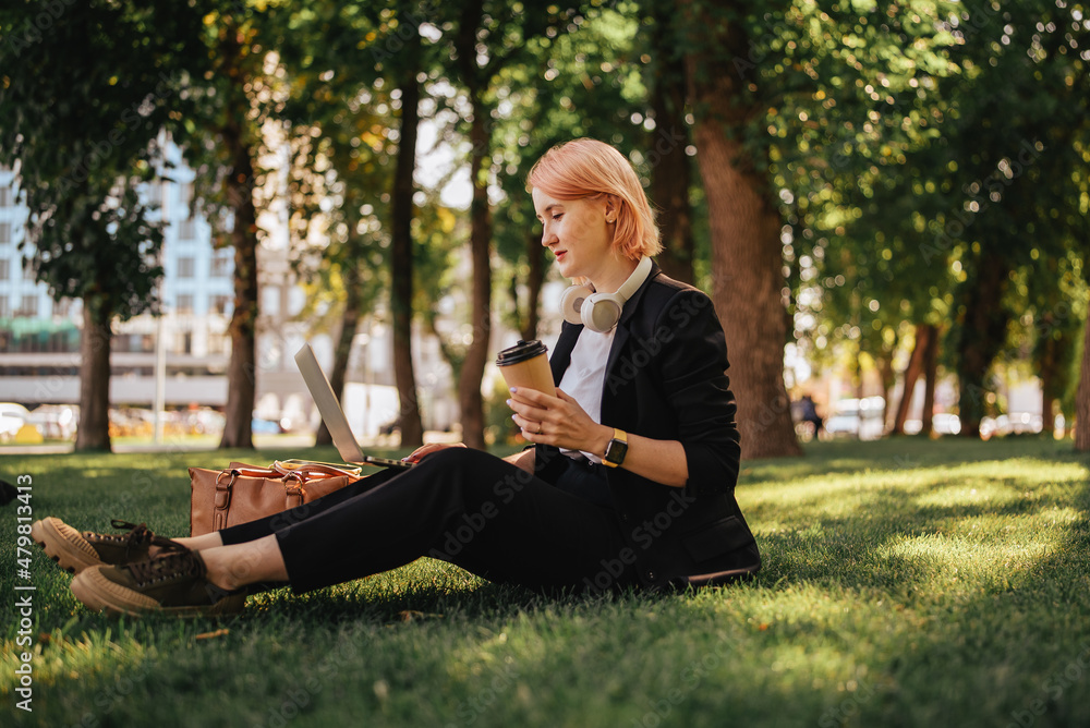 Pretty young caucasian woman go for a walk at park with coffe and laptop. Working outdoors Pretty young caucasian woman go for a walk at park with coffe and laptop. Working outdoors