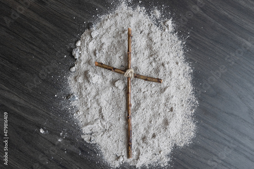 Simple wood Christian cross on ashes on a dark wood background with copy space