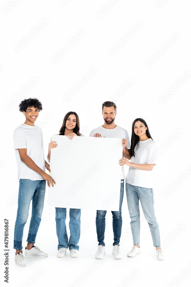 full length view of happy multiethnic friends in jeans holding blank placard on white. full length view of happy multiethnic friends in jeans holding blank placard on white.