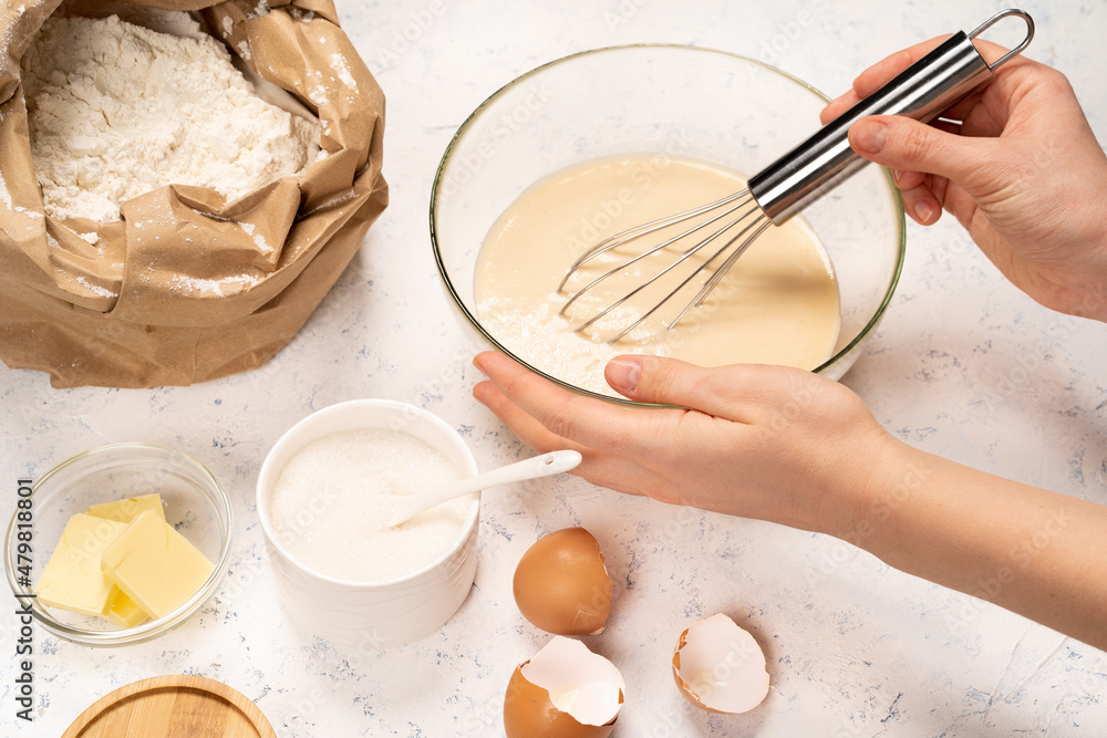 the process of making dough for pancakes with ingredients on a light table, eggs and flour are whipped with a mixer the process of making dough for pancakes with ingredients on a light table, eggs and flour are whipped with a mixer