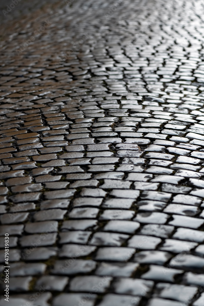 Old cobblestone street in Iserlohn Sauerland Germany. Historic basalt ashlars and blocks reflecting sunshine after rain. Wet shiny pavement surface structure, background with high contrast. Old cobblestone street in Iserlohn Sauerland Germany. Historic basalt ashlars and blocks reflecting sunshine after rain. Wet shiny pavement surface structure, background with high contrast.