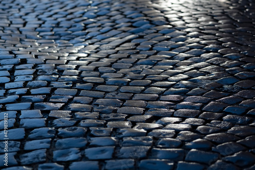 Cobblestone street in Iserlohn Sauerland Germany. Wet shiny historic basalt ashlars or blocks reflecting blue sky and sunshine after rain. Old pavement background with typical surface and structure. photo