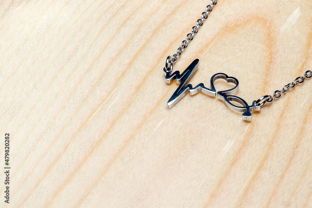 pendant cardiogram, heart, stethoscope on a chain on a wooden background, with copy space pendant cardiogram, heart, stethoscope on a chain on a wooden background, with copy space