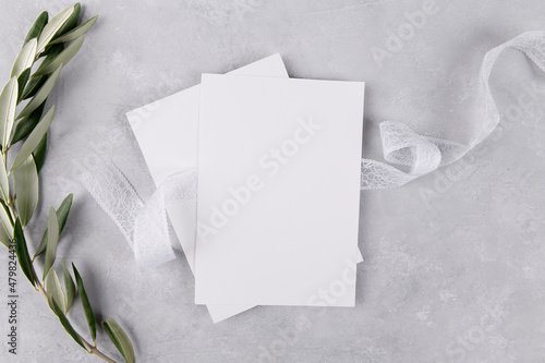 Two blank wedding invitation stationery card mockup on grey stone table background with olive branches, 5x7