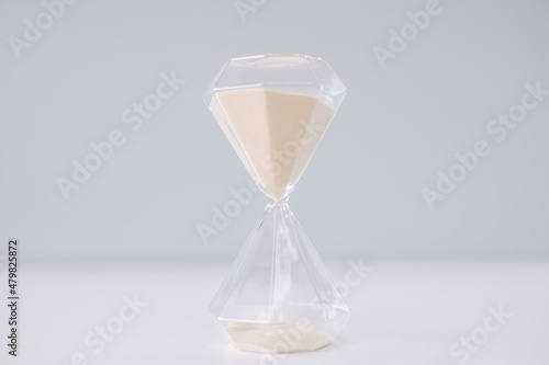 A sandglass made of glass with sand inside flowing from high to low.