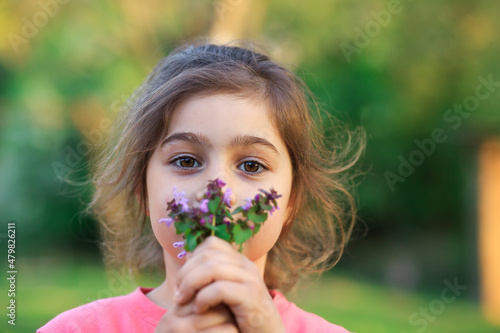 Little cute girl with pinc flowers. Child  playing in summer garden. Kids gardening. Children play outdoors. Toddler kid with flower bouquet for birthday or mother s day. photo