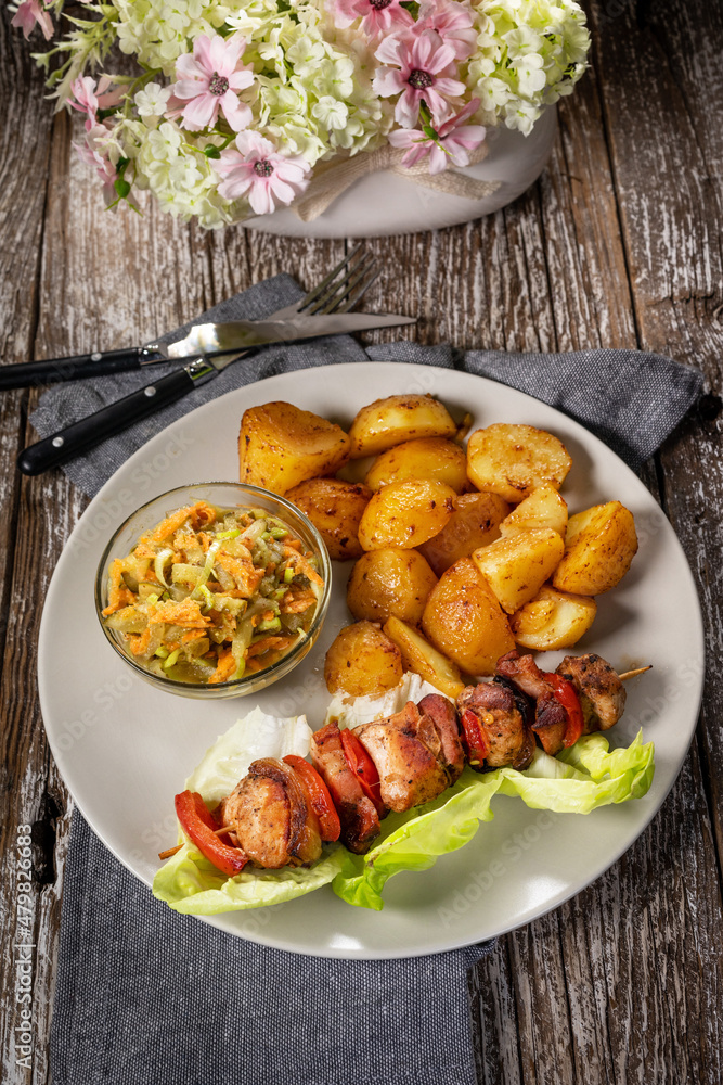 Shish kebab served with roasted potatoes and salad. Shish kebab served with roasted potatoes and salad.