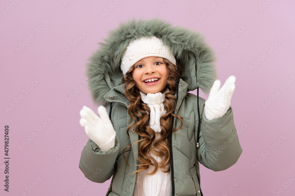 a little girl in a warm jacket and a knitted white hat with curly hair. a child in a warm winter jacket. cold season. a little girl in a warm jacket and a knitted white hat with curly hair. a child in a warm winter jacket. cold season.