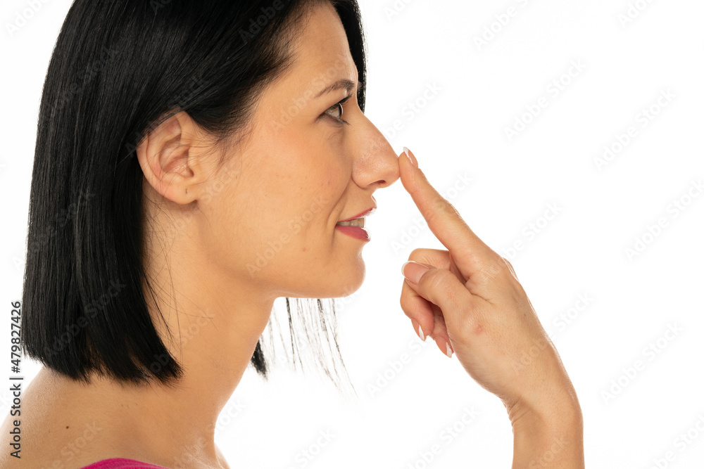 Middle aged woman touches her nose with her finger Middle aged woman touches her nose with her finger