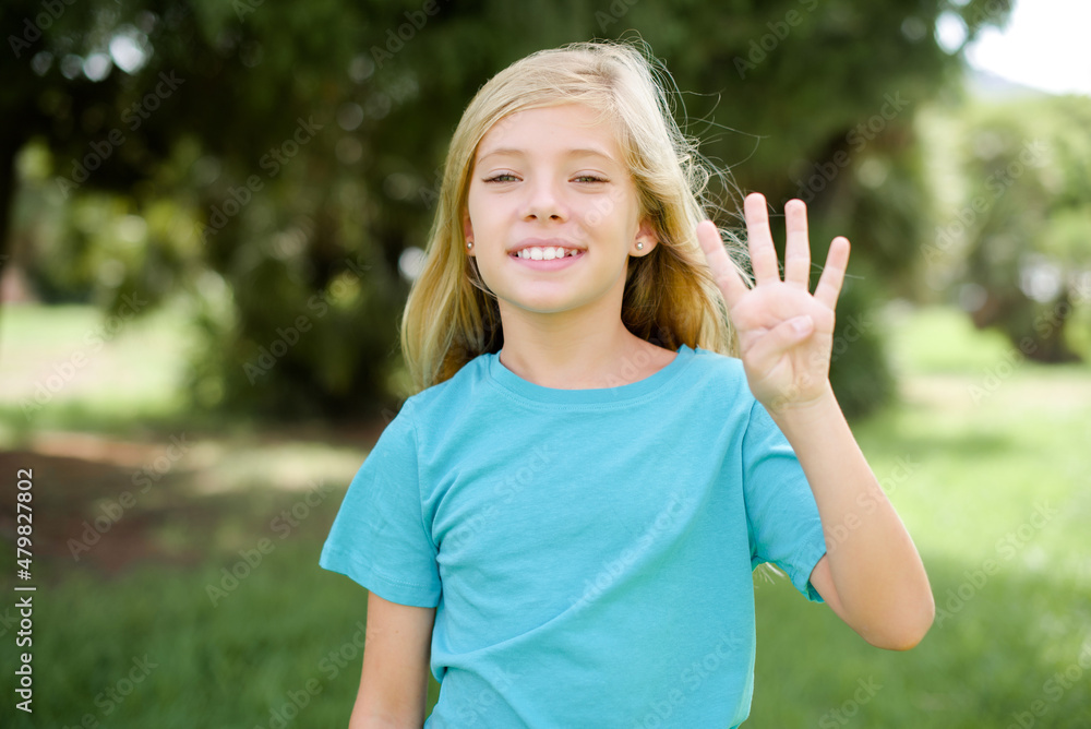 Caucasian little kid girl wearing blue T-shirt standing outdoors showing and pointing up with fingers number four while smiling confident and happy.
