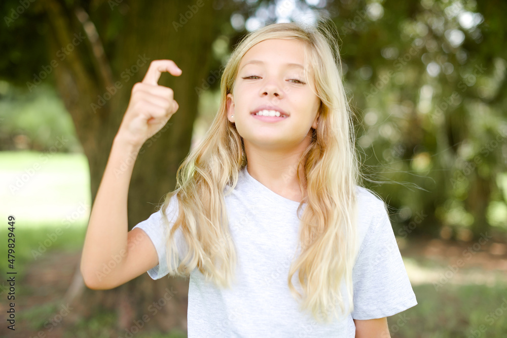 Caucasian little kid girl wearing white T-shirt standing outdoors pointing up with fingers number nine in Chinese sign language Jiu Caucasian little kid girl wearing white T-shirt standing outdoors pointing up with fingers number nine in Chinese sign language Jiu