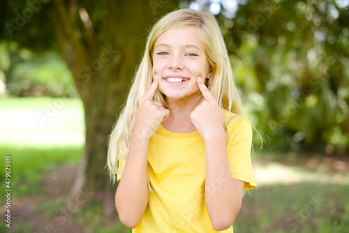 Fotografie Happy beautiful Caucasian little kid girl wearing yellow T-shirt standing outdoo