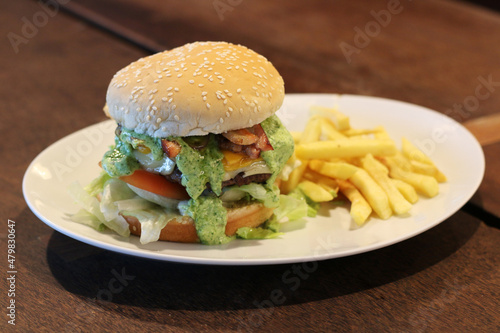 Beef sandwich with tomato, onion, bacon, green sauce and french fries