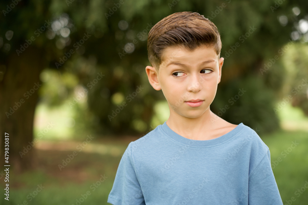 beautiful Caucasian little kid boy wearing yellow T-shirt standing outdoors looking aside into empty space thoughtful beautiful Caucasian little kid boy wearing yellow T-shirt standing outdoors looking aside into empty space thoughtful