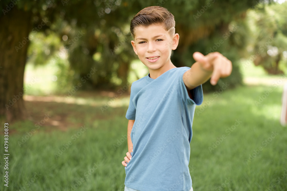 beautiful Caucasian little kid boy wearing blue T-shirt standing outdoors pointing at camera with a satisfied, confident, friendly smile, choosing you beautiful Caucasian little kid boy wearing blue T-shirt standing outdoors pointing at camera with a satisfied, confident, friendly smile, choosing you