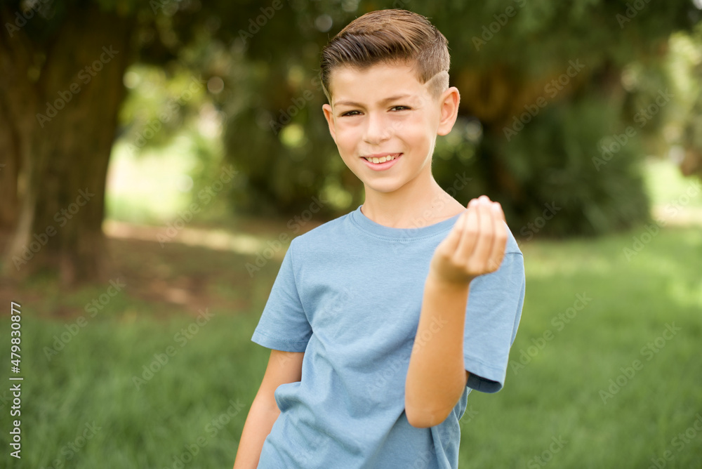 beautiful Caucasian little kid boy wearing blue T-shirt standing outdoors inviting to come with hand. Happy that you came beautiful Caucasian little kid boy wearing blue T-shirt standing outdoors inviting to come with hand. Happy that you came