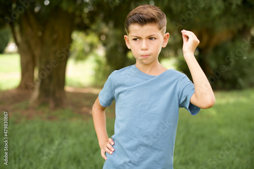 beautiful Caucasian little kid boy wearing blue T-shirt standing outdoors angry gesturing typical italian gesture with hand, looking to camera