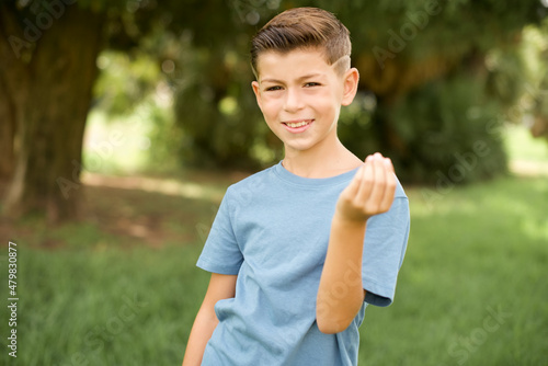 Fototapeta Naklejka Na Ścianę i Meble -  beautiful Caucasian little kid boy wearing blue T-shirt standing outdoors inviting to come with hand. Happy that you came