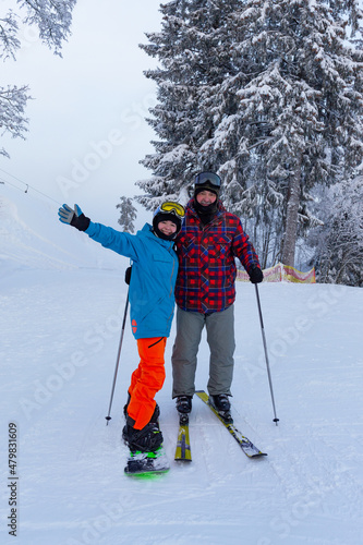 father skiing and daughter snowboarding skiing on the slope