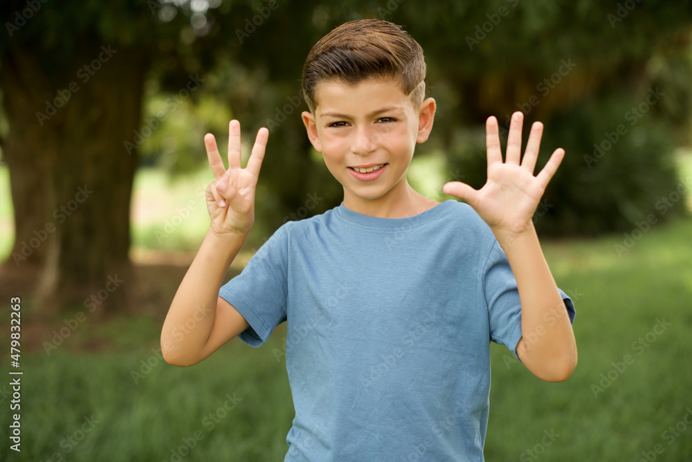 beautiful Caucasian little kid boy wearing blue T-shirt standing outdoors showing and pointing up with fingers number eight while smiling confident and happy. beautiful Caucasian little kid boy wearing blue T-shirt standing outdoors showing and pointing up with fingers number eight while smiling confident and happy.