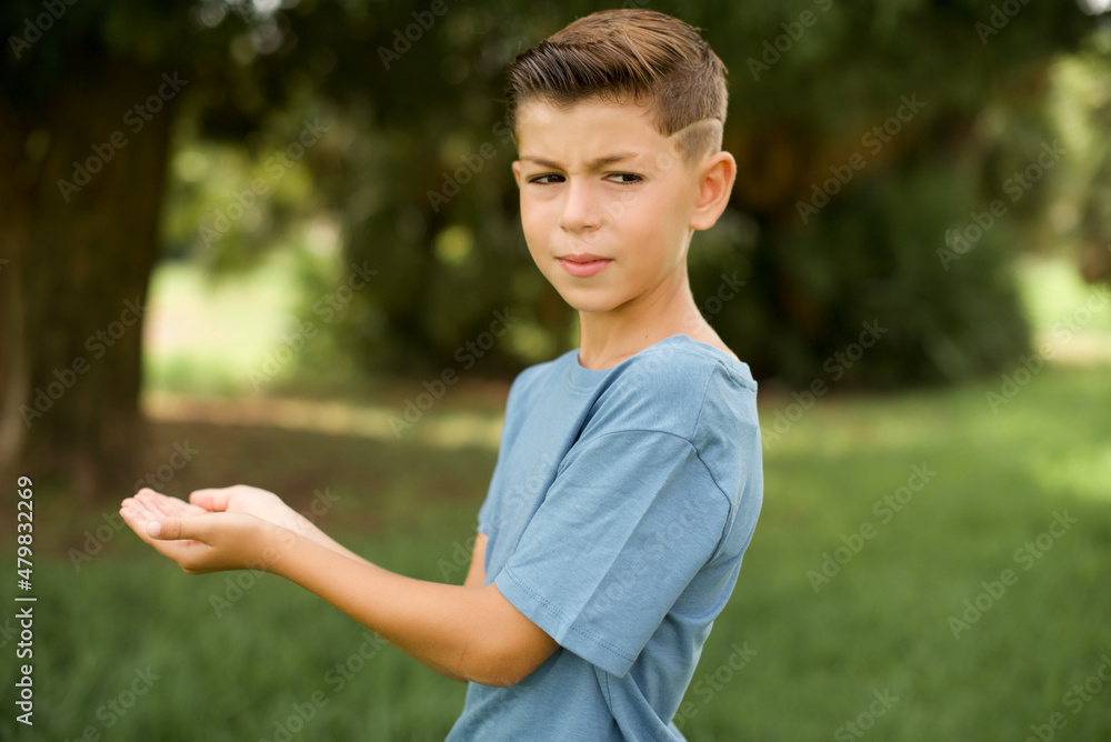 beautiful Caucasian little kid boy wearing blue T-shirt standing outdoors pointing aside with hands open palms showing copy space, presenting advertisement smiling excited happy beautiful Caucasian little kid boy wearing blue T-shirt standing outdoors pointing aside with hands open palms showing copy space, presenting advertisement smiling excited happy