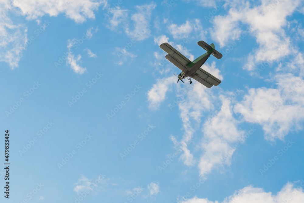 Fototapeta premium Green biplane, retro airplane flying in blue sky and doing stunts at Air Show. Performance, extreme, aerobatic, sport and aircraft concept