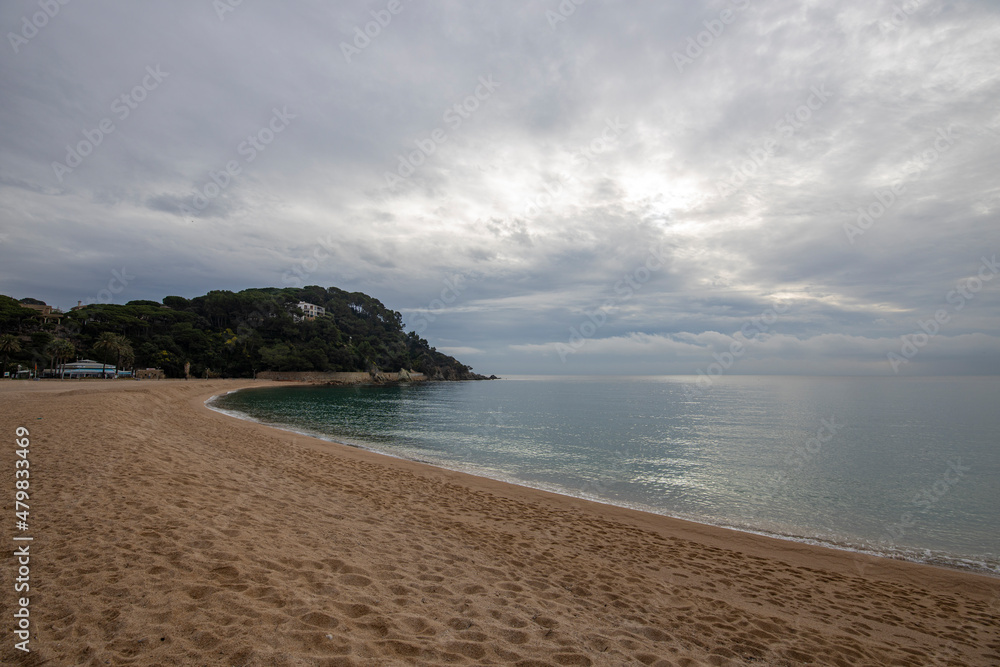 Sandy coast and stones under a cloudy sky on the Costa Brava, Spain. Picturesque seascape with a coast.