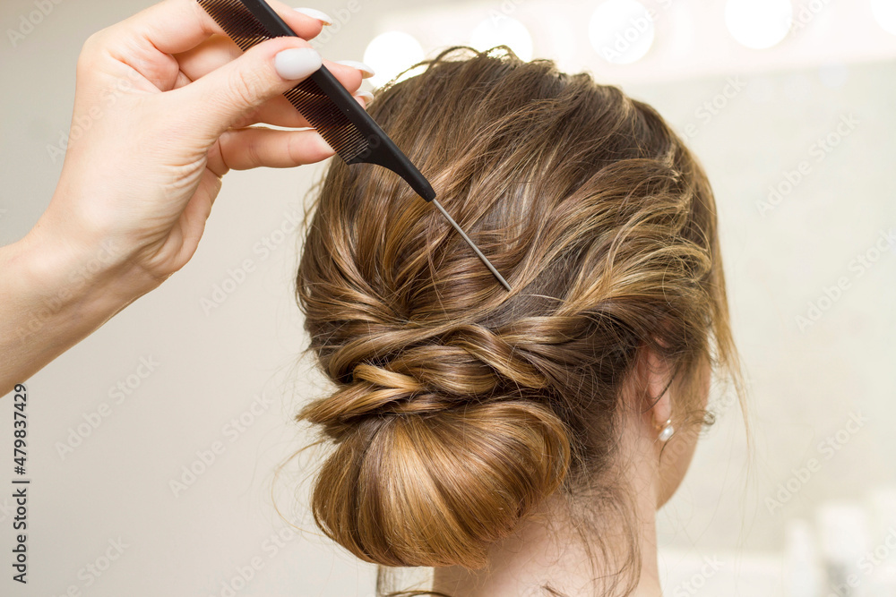 Naklejka premium The stylist performs the hairstyle, hair styling in the salon.