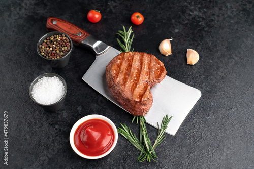 Heart shaped grilled beef steak with arrow on knife for valentine's day on stone background
