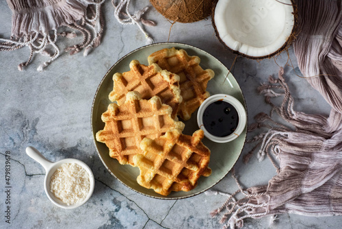 Healthy dessert: thick coconut waffles on a beautiful plate on a gray background. Top view.