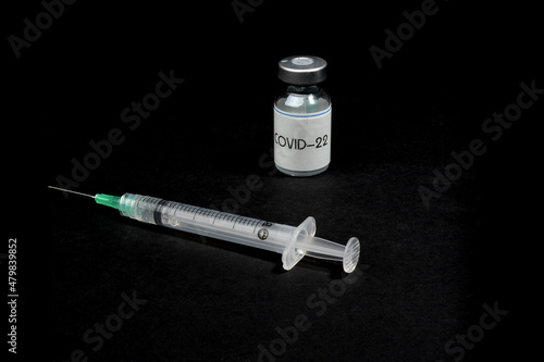 COVID-22 vaccine with a syringe, on a black background