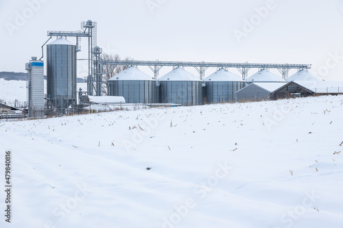 Silos in a cold winter day and stubble corn field covered with snow in foreground