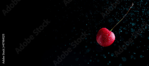 Popsicle with fresh cherries on a dark background, dynamic shot with action, splash, water drops and bokeh. Fresh fruit floating or levitating shotwith water droplet and dark background. photo