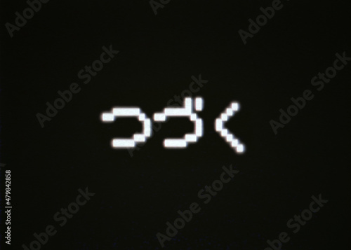 The japanese text To be continued (Tsuzuku in Hiragana characters), old 8-bit pixellated retro characters on a fake computer screen.
