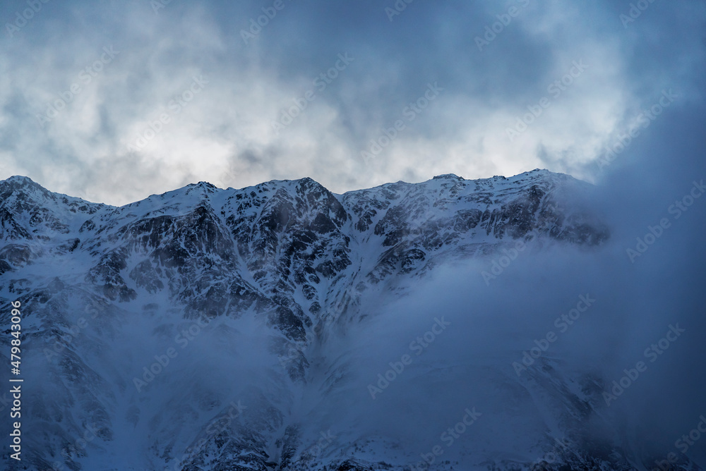 Fototapeta premium Beautiful winter mountains landscape on the sunrise. High snow covered mountains in the fog. Georgia, Kazbegi. 