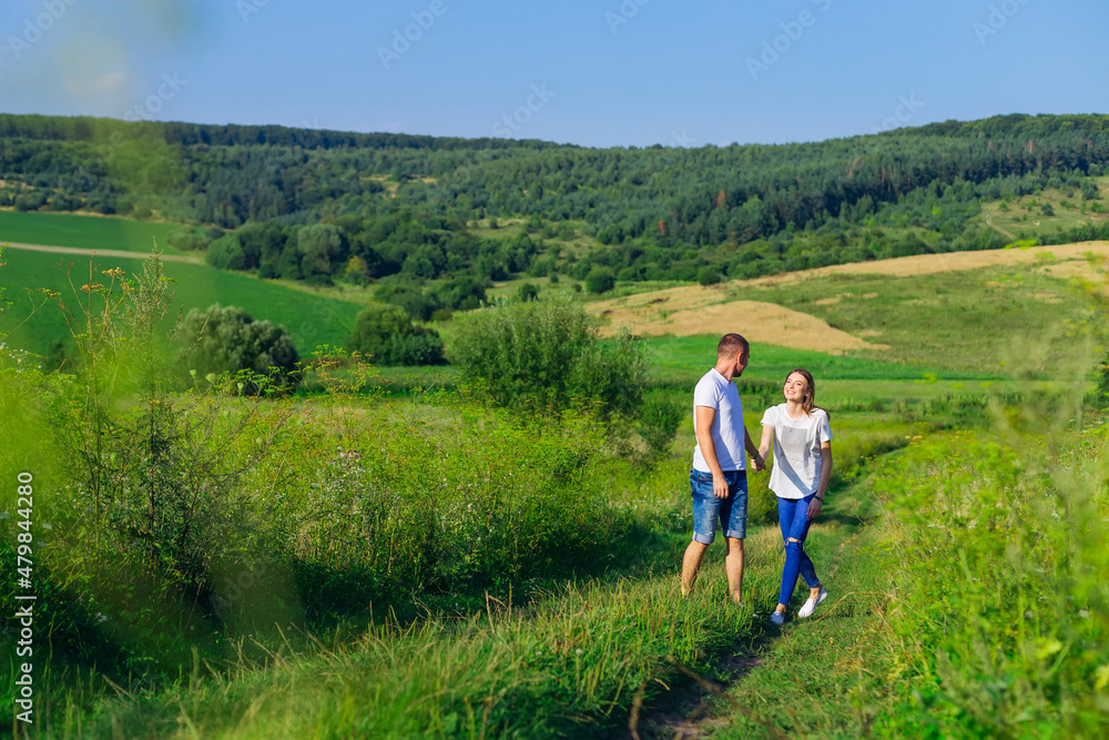 couple in love walking on a path in the middle of a field. meado couple in love walking on a path in the middle of a field. meado