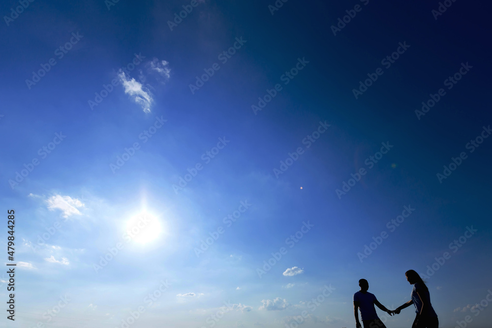 couple in casual wear holding hands and walking on blue sky back couple in casual wear holding hands and walking on blue sky back