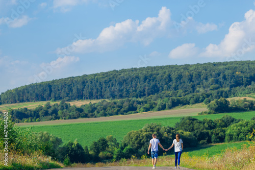 guy and girl hold hands and look at meadow and forest. back view © Ivan