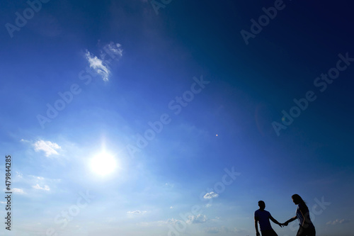 couple in casual wear holding hands and walking on blue sky back