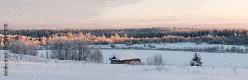 Wonderful village landscape. Beautiful view from a hill to the bathhouse, a large frozen lake, a snow-covered forest and the sky. © koldunova