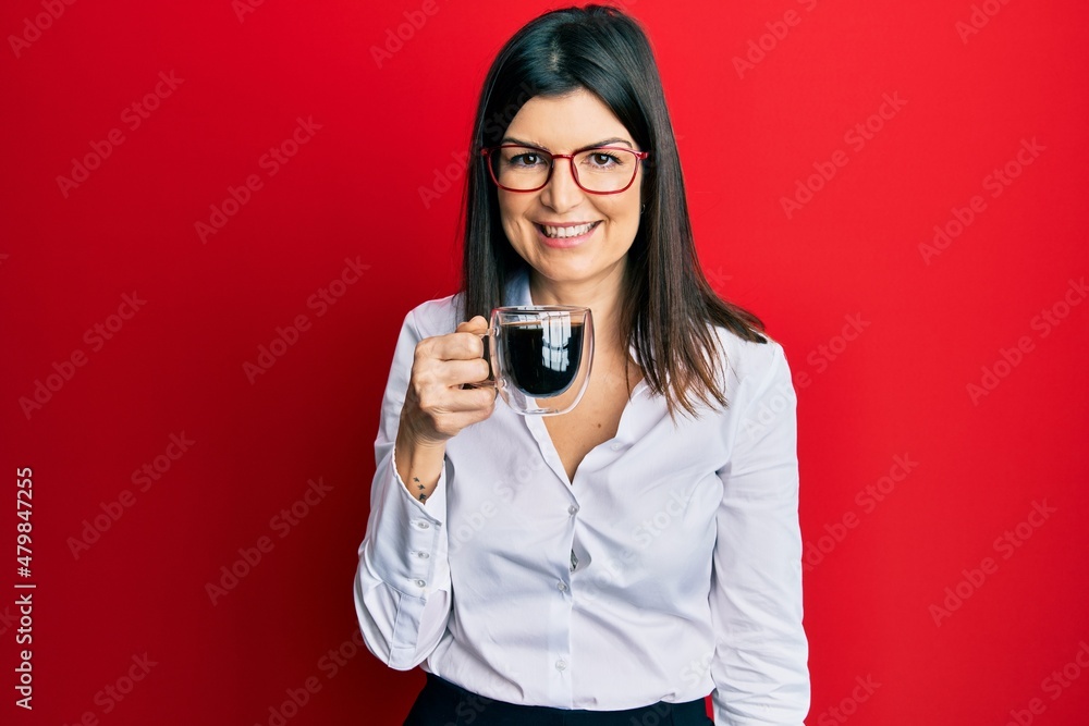 Young hispanic woman wearing business style drinking cup of coffee looking positive and happy standing and smiling with a confident smile showing teeth Young hispanic woman wearing business style drinking cup of coffee looking positive and happy standing and smiling with a confident smile showing teeth