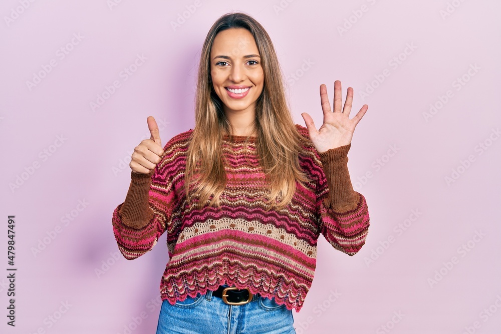 Beautiful hispanic woman wearing hippie sweater showing and pointing up with fingers number six while smiling confident and happy. Beautiful hispanic woman wearing hippie sweater showing and pointing up with fingers number six while smiling confident and happy.