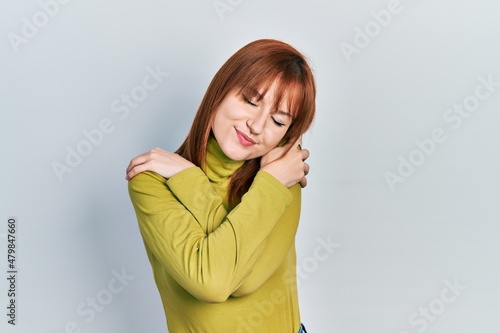 Redhead young woman wearing turtleneck sweater hugging oneself happy and positive, smiling confident. self love and self care © Krakenimages.com