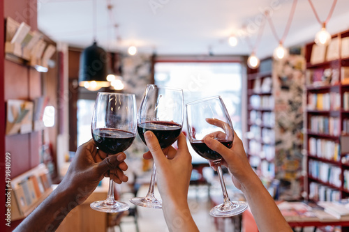 Foto toasting raised hands holding glasses in a book cafe - celebration