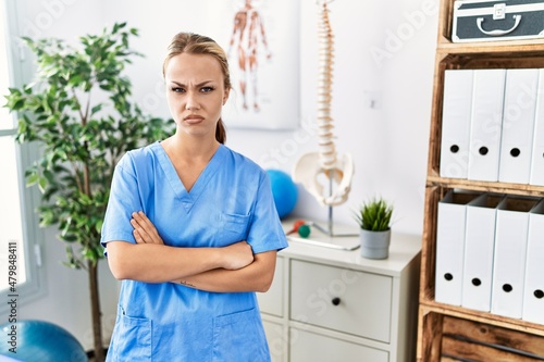Young caucasian woman working at pain recovery clinic skeptic and nervous  disapproving expression on face with crossed arms. negative person.