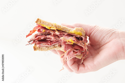 Hand Holding Smoked Meat Sandwich with Bite